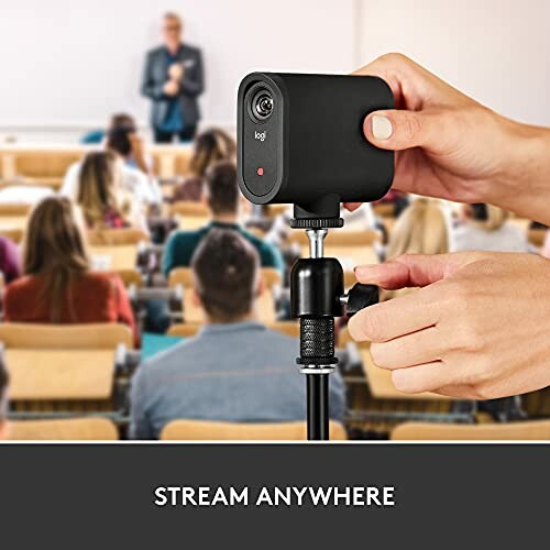 Person adjusting a portable camera in a lecture hall.