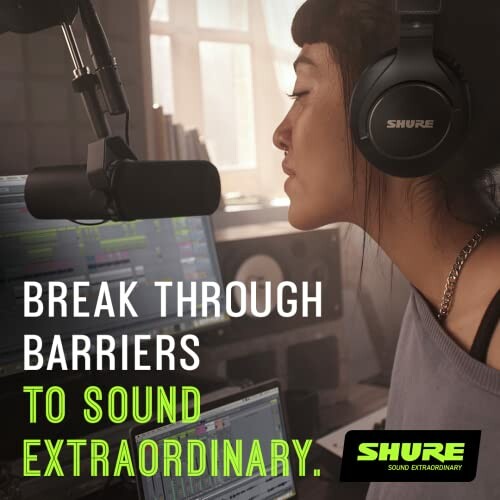 Woman using microphone and headphones in recording studio